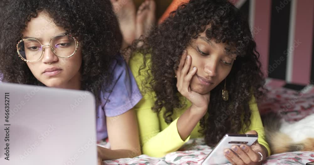 Gen Z female friends using a laptop and smartphone at home