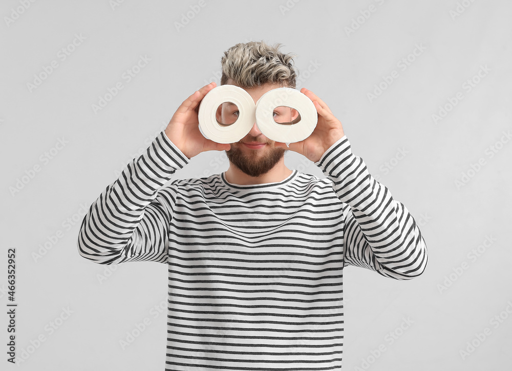 Funny young man with toilet paper on light background Funny young man with toilet paper on light background
