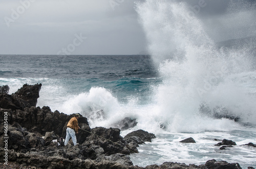 Fischer mit Angel auf Vulkaninsel Pico mit Meeresbrandung