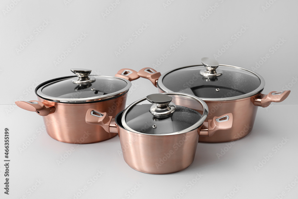 Golden cooking pots with glass lid on light background Golden cooking pots with glass lid on light background
