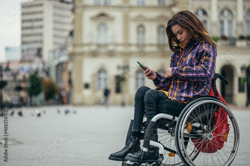 Принти на полотні Woman in wheelchair using a smartphone while out in the city