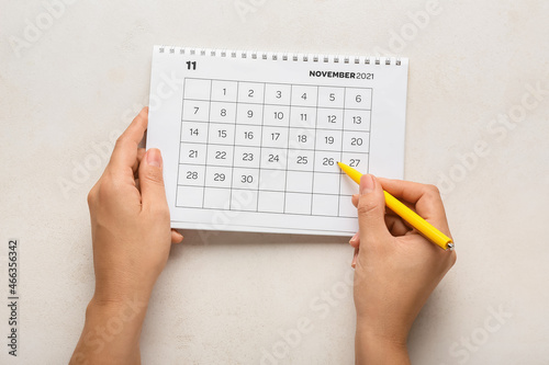 Woman marking date of Black Friday in calendar on white background
