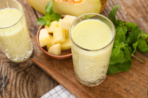 Glasses of tasty melon milkshake on wooden background, closeup
