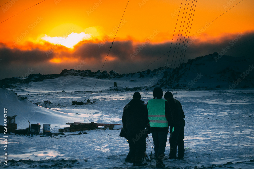 People work in cold difficult conditions in winter in the mountains, at dawn 