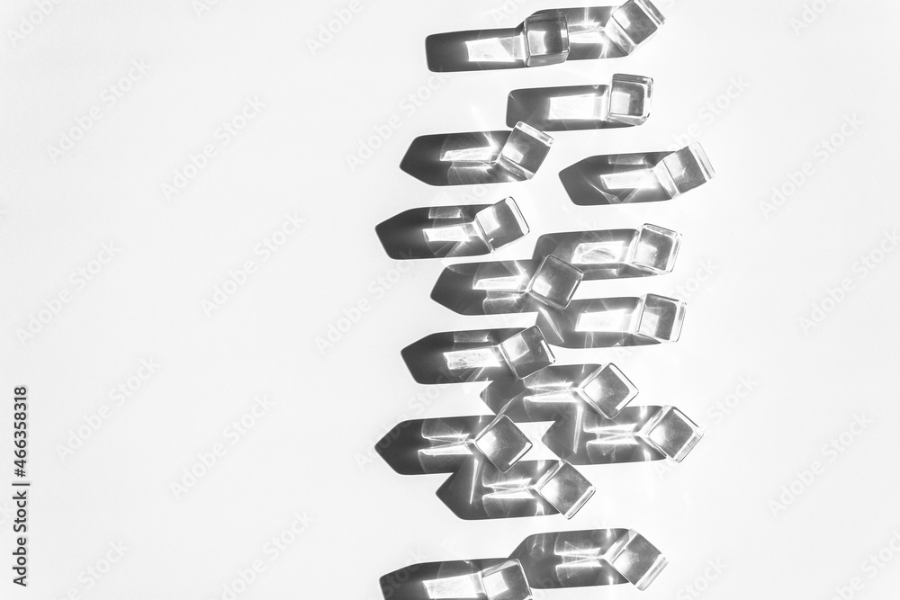Layout with transparent plastic cubes and sharp shadows of sun at the background. Flat lay. Copy space. Black and white photo. Layout with transparent plastic cubes and sharp shadows of sun at the background. Flat lay. Copy space. Black and white photo.