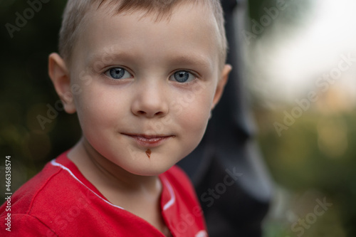 Little cute boy got dirty in ice cream. he looks at the camera and smiles. close-up image