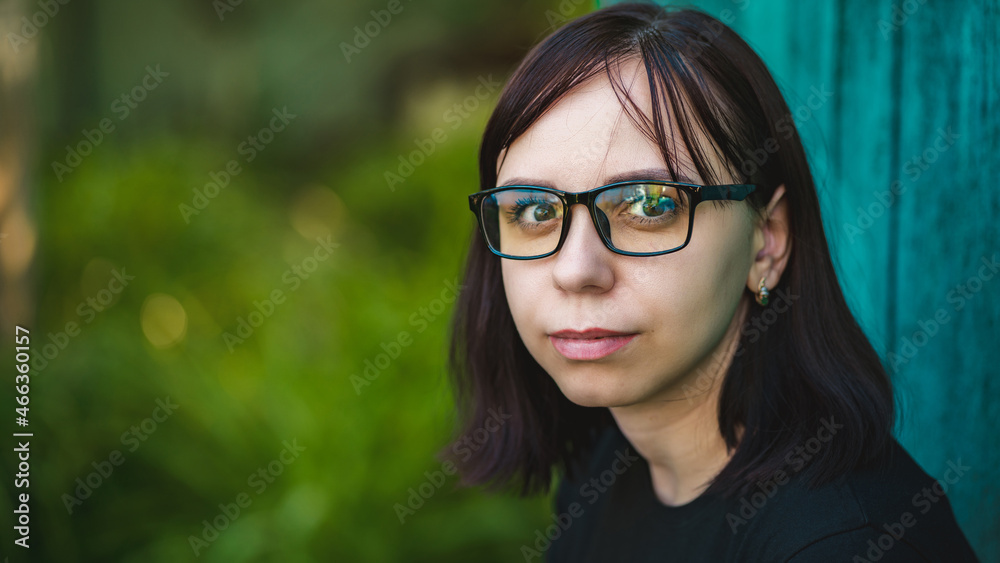 Portrait of a brunette with glasses in nature. Close-up of a woman with black-rimmed glasses Portrait of a brunette with glasses in nature. Close-up of a woman with black-rimmed glasses