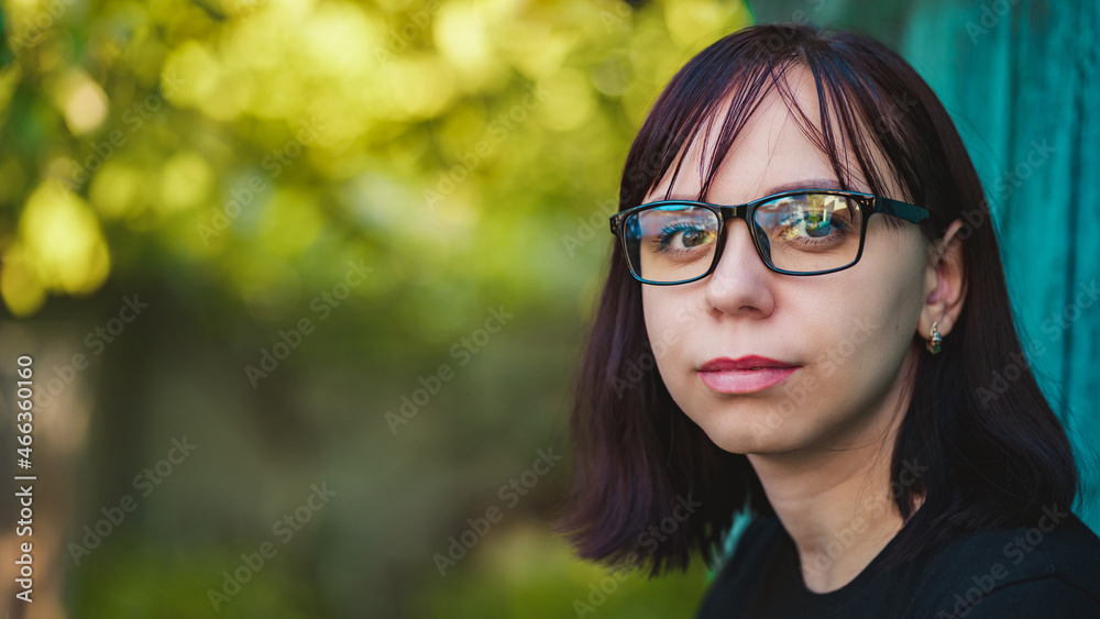 Portrait of a brunette with glasses in nature. Close-up of a woman with black-rimmed glasses Portrait of a brunette with glasses in nature. Close-up of a woman with black-rimmed glasses
