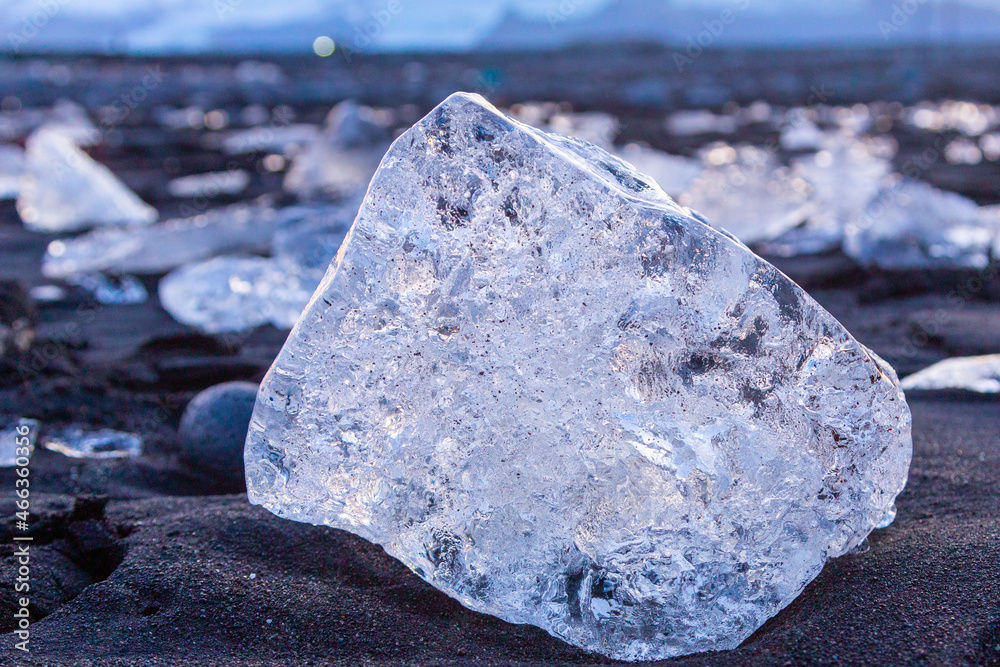 Closeup view of chunks of ice on the black sands of Diamond Beach in Iceland at sunset.