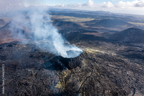 Aerial drone view of Fagradsfjall volcano in Iceland. Smoke is spewing out of volcano, black lava landscape.