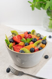 Fresh, healthy chopped fruit salad in a bowl on white  background. Top view. Strawberry, blueberry, kiwi, orange, mint..