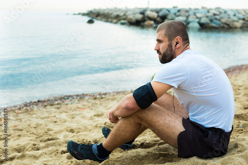 Athletic man resting after strenuous training on the seashore