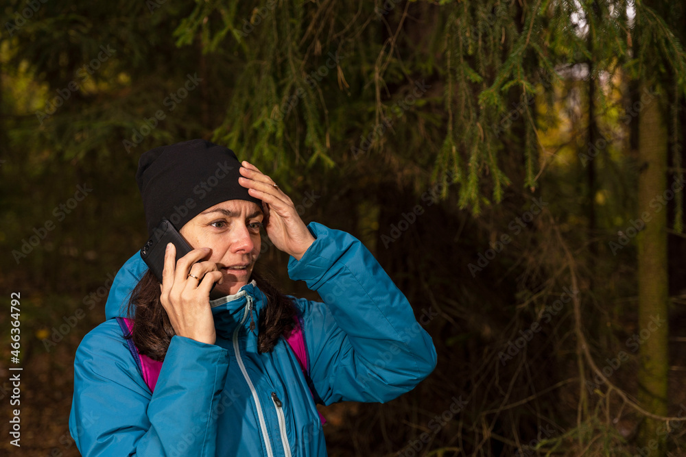 A tourist girl is talking on the phone in the forest, a tourist got lost in the forest. Call for help