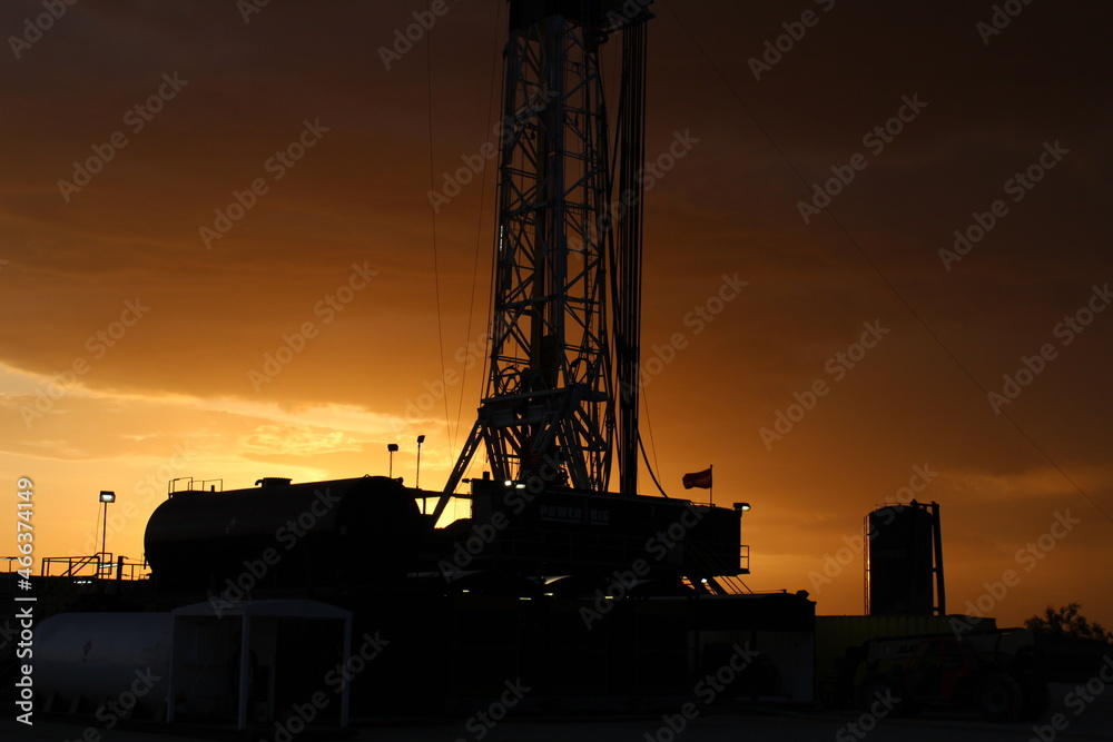 Drilling rig in West Texas with a dark orange sky during the sunset. Drilling rig in West Texas with a dark orange sky during the sunset.