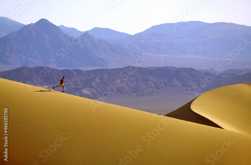 Bucky Brownell running dunes at Stovepipe Wells w  Funeral Mts in background  at Death Valley National Park  CA   USA