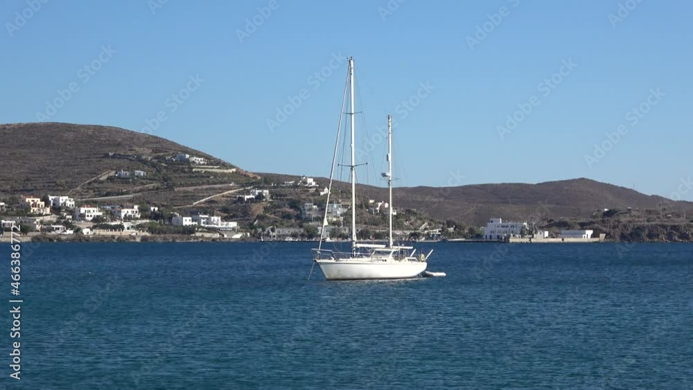 Anchored sailboat in the bay. View of an anchored white sailboat near the coast of Finikas village at the greek island of Syros. Anchored sailboat in the bay. View of an anchored white sailboat near the coast of Finikas village at the greek island of Syros.