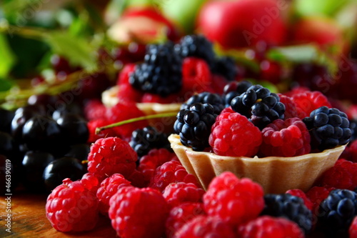 Summer berries dessert still-life. Mix ripe fresh berries bramble, blackberry, raspberries in basket, cherries close up on blurred background of bird cherry and apple. Selective focus on first basket