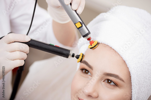 Closeup microcurrent procedure for lifting skin face treatment young woman from spa clinic