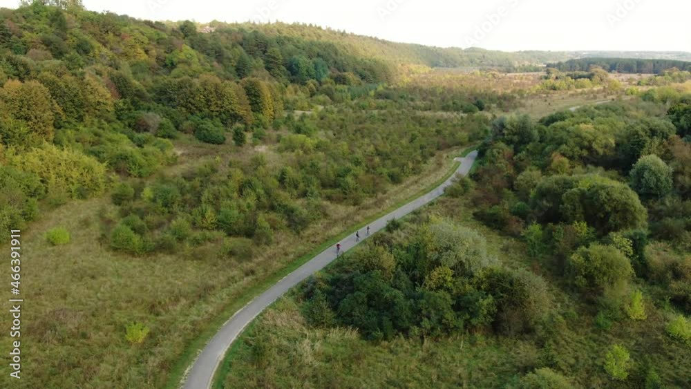 Team of cyclist ride on majestic countryside road in Lithuania, aerial drone view