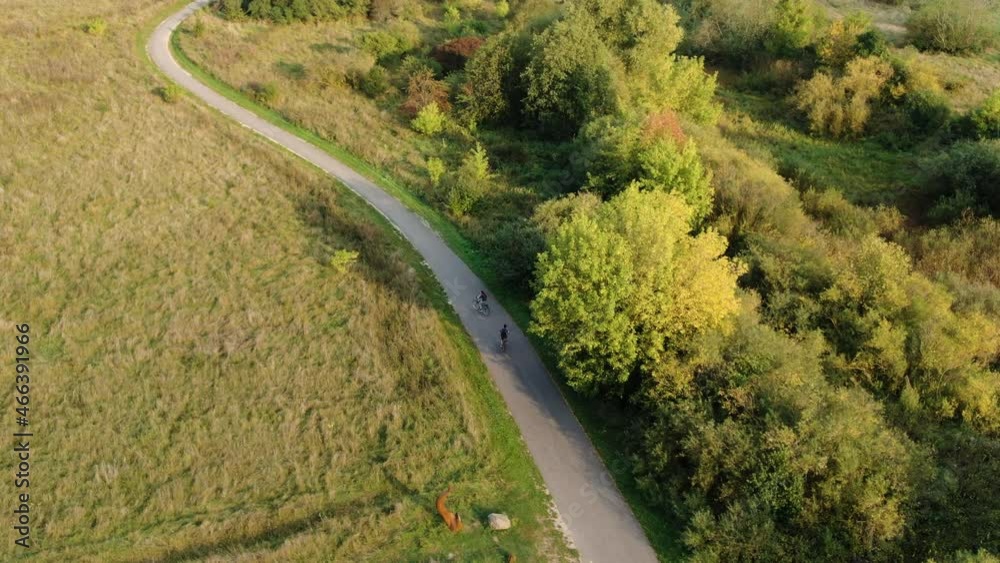 Cyclist ride on asphalt road in majestic rural landscape of Lithuania, aerial drone view
