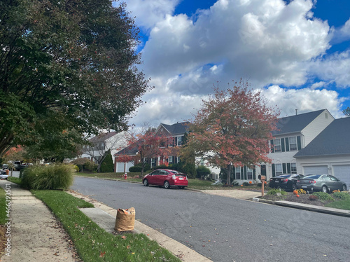 Lorton, Virginia, USA - October 31, 2021: Suburban Homes Surrounded by Trees Changing Colors and Leaves Falling from the Branches on a Bright Autumn Morning photo
