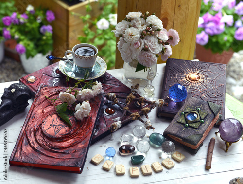 Vintage summer still life with old spell book, runes, crystals and magic object on witch table.