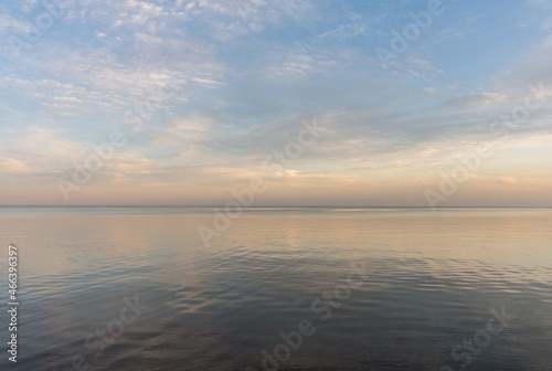 Calm evening sea surface with clear blue sky. Evening seascape.