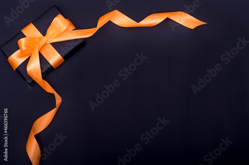 Valokuva gift i n black paper with orange ribbon on a black background year of the tiger
