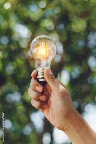 Hand holding light bulb with green background. idea solar energy