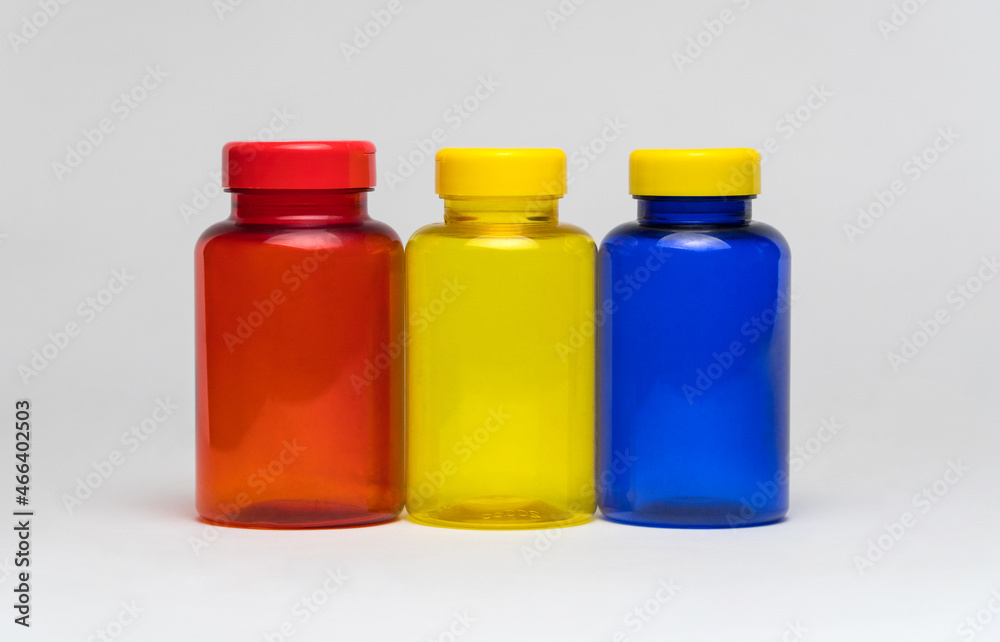 Multi colored transparent plastic pill jars on a white background. Isolated