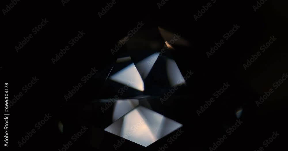 Rotation of the diamond. Reflection of light from the facets of the rhinestone. Close-up of a diamond on a black background