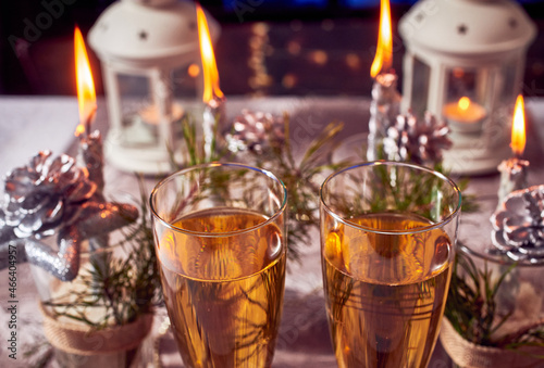 Silver candles, lights, cones, glasses of champagne, Christmas decorations on the table.