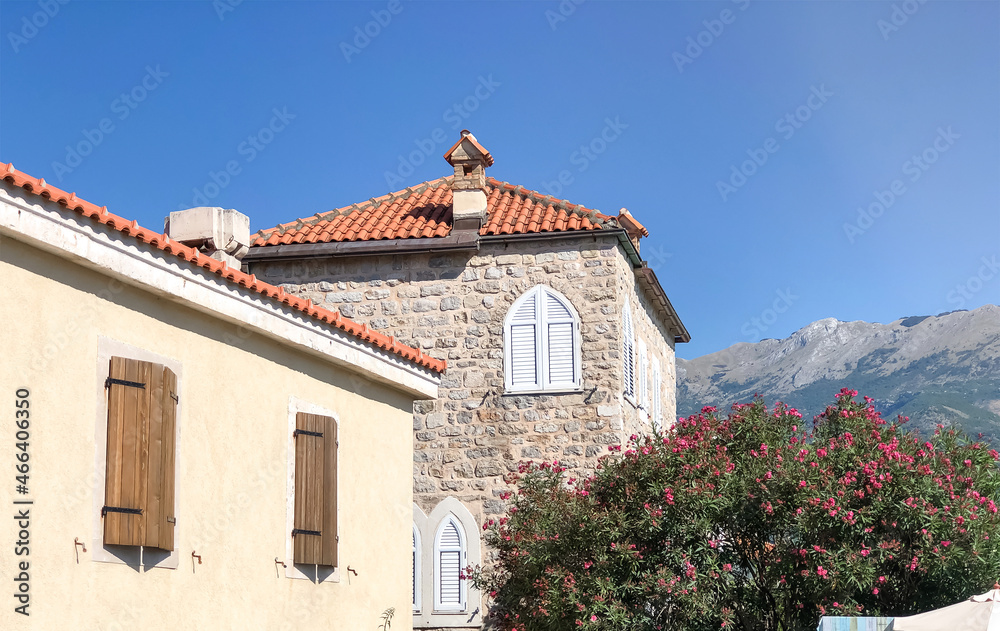 Bright traditional red and orange tiled roofs of houses against the backdrop of beautiful mountains in Montenegro