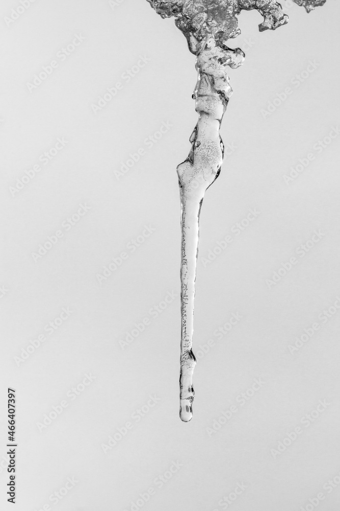 a long thin icicle on a gray sky background, black and white photo