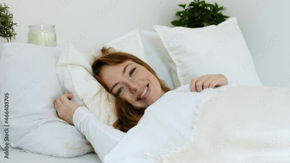 Young Caucasian woman in bright white bedroom is lying in cozy bed. beautiful sleeping female wakes up in bed in morning and opens her eyes. serene morning in bedroom. Young Caucasian woman in bright white bedroom is lying in cozy bed. beautiful sleeping female wakes up in bed in morning and opens her eyes. serene morning in bedroom.