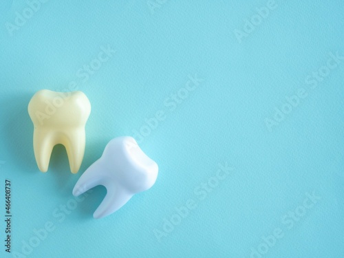 Teeth fake white healthy and yellow sick on a blue background with place for text.