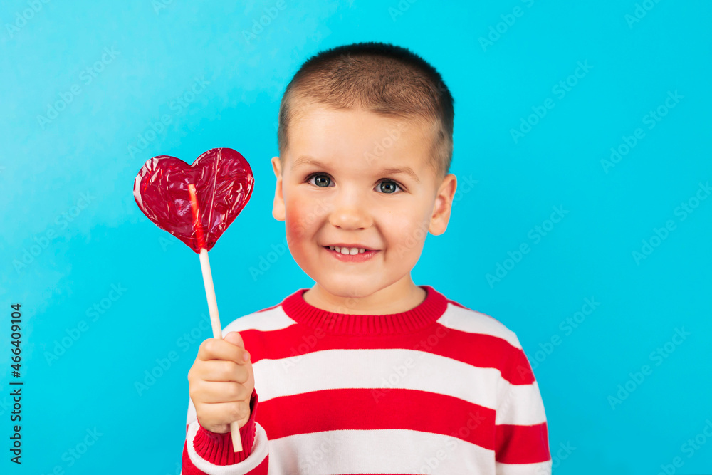 Happy laughing child Boy with candy heart Valentine's Day, blue background. 14 February. Happy laughing child Boy with candy heart Valentine's Day, blue background. 14 February.