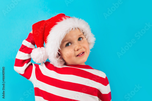 Funny child in a Santa hat, blue background. Holidays, Traditions, Christmas concept.