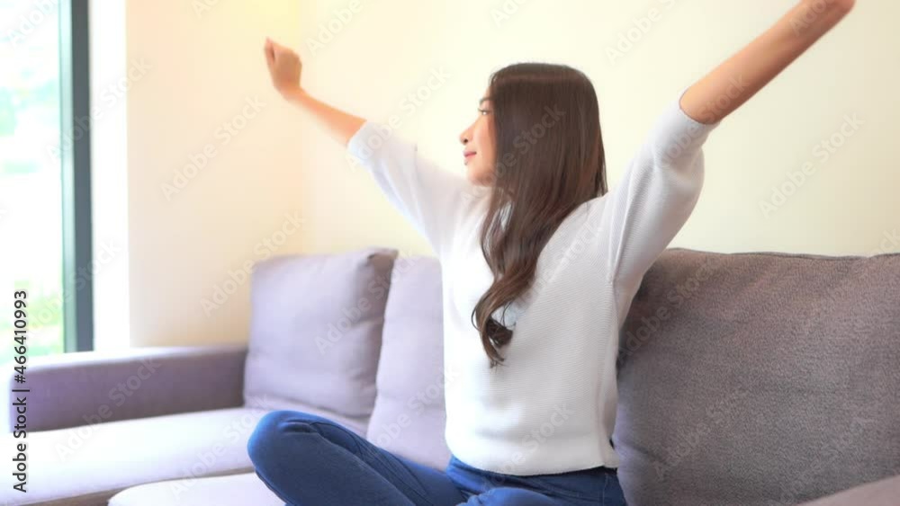 Tired woman stretching hands with eyes closed enjoying peaceful chill at home. Calm young adult lady lounging on a comfortable sofa in modern living room interior. Tired woman stretching hands with eyes closed enjoying peaceful chill at home. Calm young adult lady lounging on a comfortable sofa in modern living room interior.