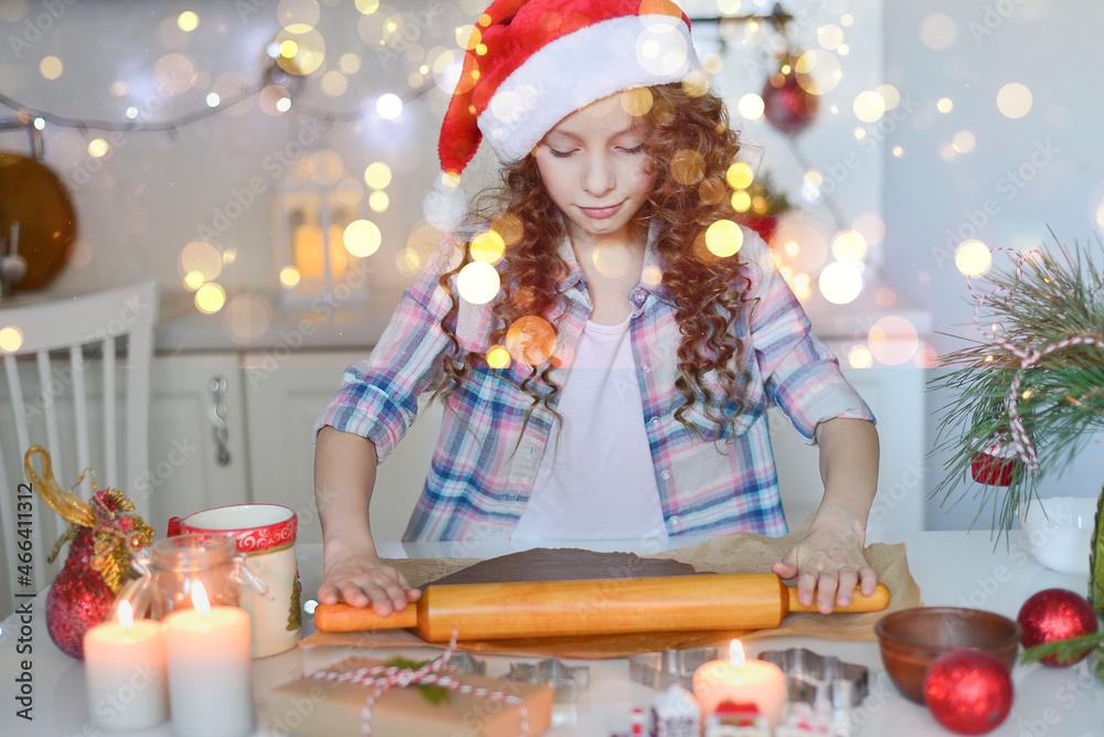 The girl is rolling out the dough for cristmas cookies. They are in the kitchen at home. Horizontal frame. This photo with bokeh. The girl is rolling out the dough for cristmas cookies. They are in the kitchen at home. Horizontal frame. This photo with bokeh.