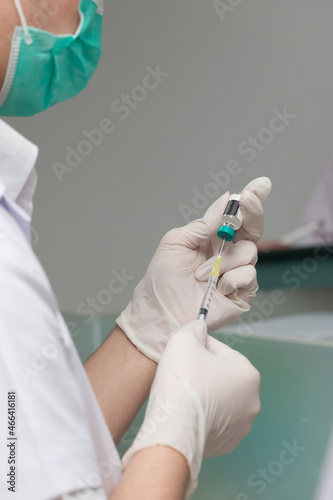 Doctor or nurse drawing vaccine bottle into syringe injection medicine, covid 19 vaccine