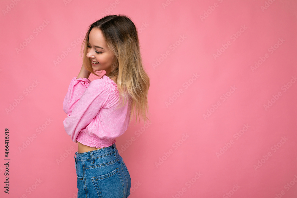 Portrait of young beautiful smiling hipster blonde woman in trendy pink crop top blouse. Sexy carefree female person posing isolated near pink wall in studio. Positive model with natural makeup. Copy Portrait of young beautiful smiling hipster blonde woman in trendy pink crop top blouse. Sexy carefree female person posing isolated near pink wall in studio. Positive model with natural makeup. Copy