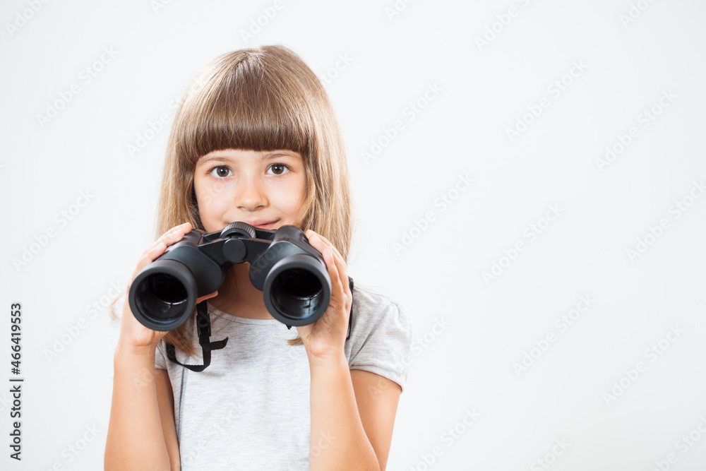 Studio shot portrait of happy little girl who is using binoculars. Copy space on gray background. Studio shot portrait of happy little girl who is using binoculars. Copy space on gray background.