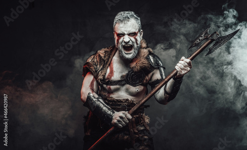 Violent and savage fighter with axe in dark smokey background
