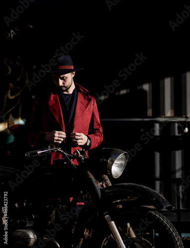 man in a coat near a vintage motorcycle