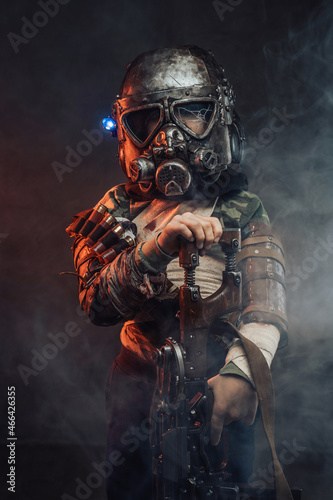 Little survivor with gas mask and gun in smokey background