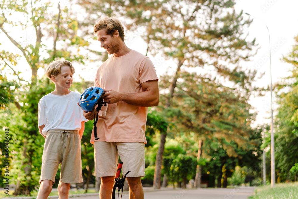 Fototapeta premium Ginger man talking with his son while teaching him how to ride bicycle