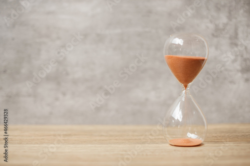 Hourglass on table, Sand flowing through the bulb of Sandglass measuring the passing time. countdown, deadline, Life time and Retirement concept