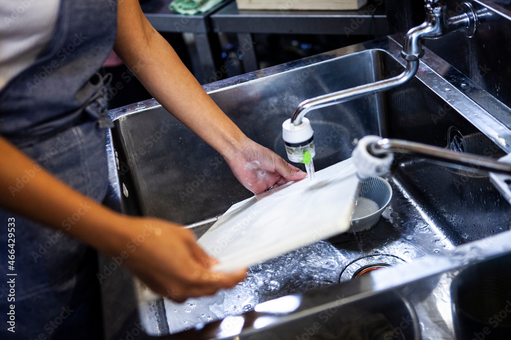 シンクで皿洗いをする女性の手元