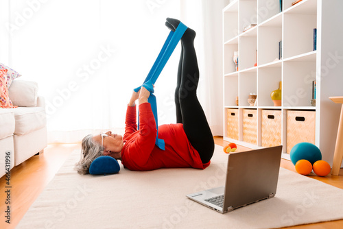 Woman stretching legs with resistance band at home photo